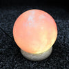 A glowing usb himalayan salt lamp ball with warm orange pink hue and natural mineral texture showing hygroscopic properties