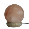 A smooth round pink usb himalayan salt lamp ball with a textured stone base showing its hygroscopic properties