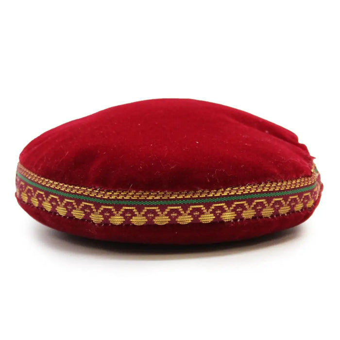 A plush round red velvet singing bowl cushion with gold and green woven decorative band, 11cm in size