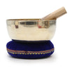 Silver-toned tibetan singing bowl with wooden mallet on a royal blue velvet singing bowl cushion with gold and red embroidery