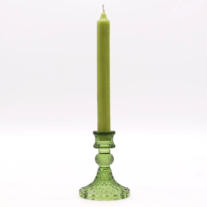 A tall olive green candle in a vintage glass candle holder with intricate cut glass detailing for candles display