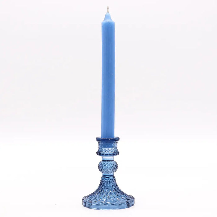 A tall slender blue vintage dinner candle stands in a matching blue faceted crystal candle holder for candles
