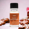 A clear glass bottle with black cap holds warm gingerbread fragrance oil labeled ancient wisdom made in england with allergen declarations
