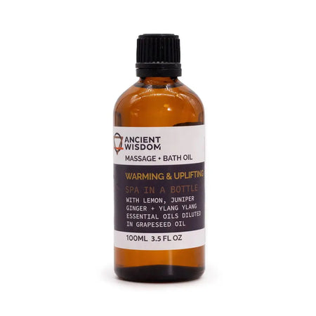 An amber glass bottle of ancient wisdom warming and uplifting massage oil with essential oils and a black cap