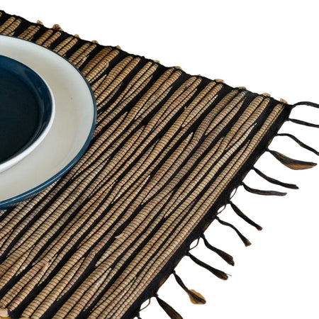 Natural woven water hyacinth placemat with black tiger striped pattern and fringed edges in brown and tan colors