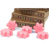 Pink flower-shaped wax melts made from palm waxes scattered in front of stacked cardboard boxes for japanese magnolia