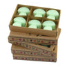 Six mint-green mushroom-shaped palm waxes wax melts in a cardboard box with decorative border patterns