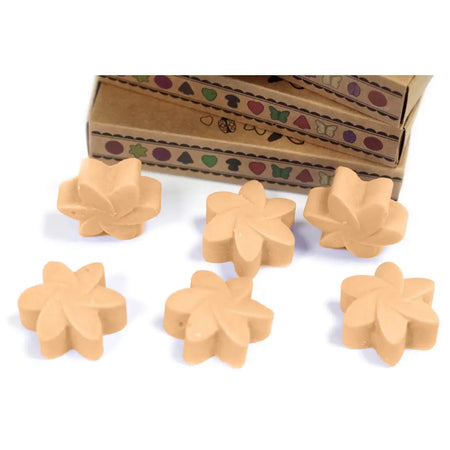Beige flower-shaped wax melts made from palm waxes with a matte finish arranged in front of decorative boxes