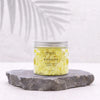 A clear glass jar with silver lid holds pale yellow banana scented whipped soap labeled ancient wisdom 120g