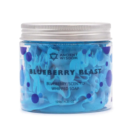 A clear glass jar with silver lid holds vibrant blue whipped soap speckled with purple dots labeled blueberry blast