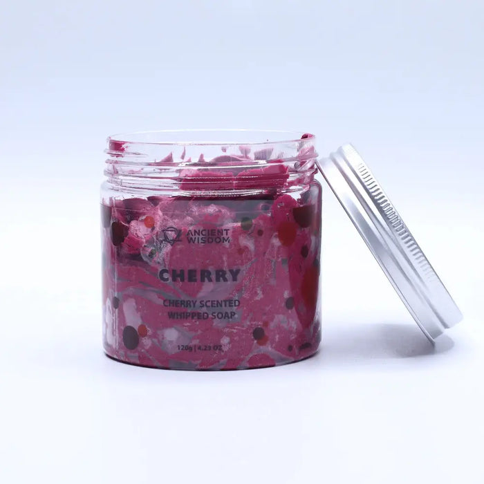 A vibrant pink cherry-scented whipped soap in a clear glass jar with silver lid and colorful speckles by ancient wisdom