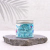 A clear glass jar with silver lid showing light blue whipped soap with pink and dark blue dots marshmallow scent 120g