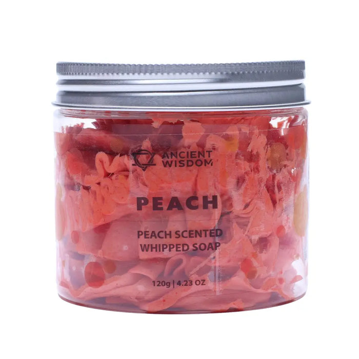 A clear glass jar with silver lid holds peach scented whipped soap with pink and orange floral pieces inside