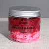 A vibrant pink and red fragranced razzle dazzle whipped soap in a clear glass jar with silver lid by ancient wisdom