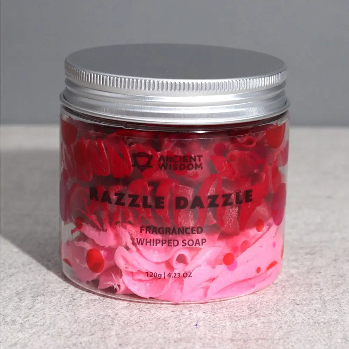 A vibrant pink and red fragranced razzle dazzle whipped soap in a clear glass jar with silver lid by ancient wisdom