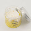 A clear glass jar with silver lid holds vanilla whipped soap with creamy white top and yellow base containing sodium cocoyl isethionate