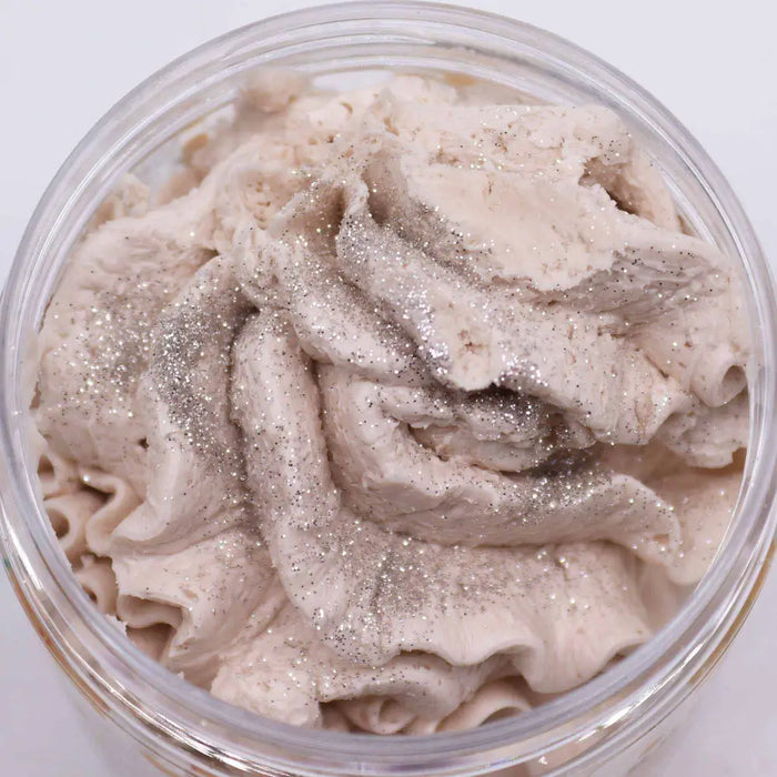 A creamy light beige whipped soap with a warm gingerbread scent and silver glitter in a clear plastic jar
