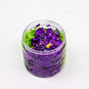 A clear glass jar of witches brew whipped soap bath bombs in purple and green with black and silver glitter decorations