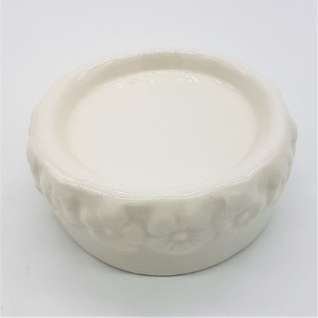 White ceramic candle stand with a glossy finish and embossed floral pattern around the rim of the candle stand