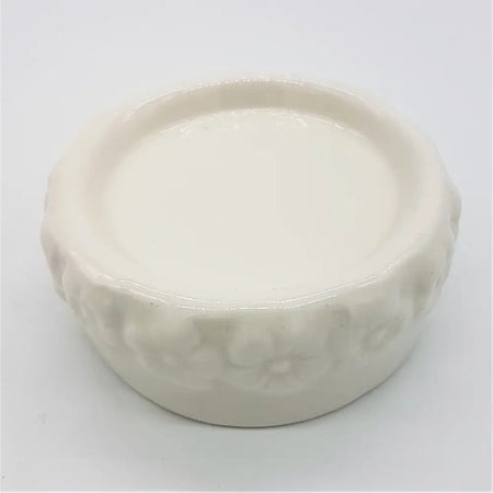 White ceramic candle stand with a glossy finish and embossed floral pattern around the rim of the candle stand