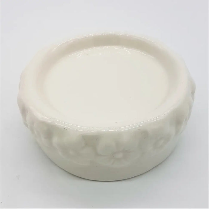 White ceramic candle stand with a glossy finish and embossed floral pattern around the rim of the candle stand