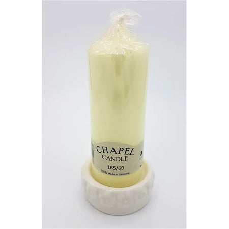 A pale yellow chapel ceramic candle on a white ceramic candle stand with flower design made in Germany