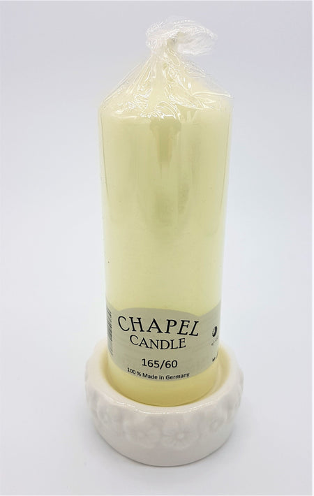 A pale yellow chapel ceramic candle on a white ceramic candle stand with flower design made in Germany