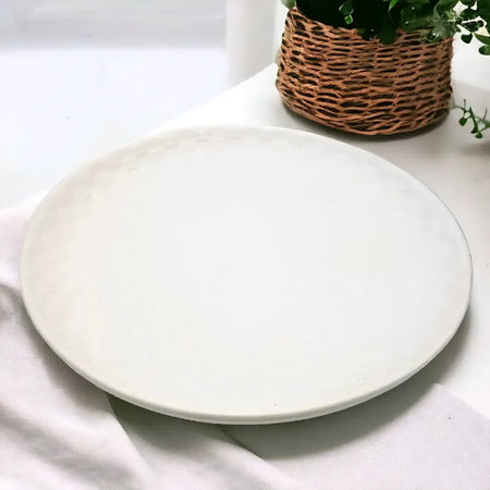 A smooth off-white ceramic plate with a subtle textured rim featuring a white ceramic weave design