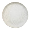 White ceramic plate with a white hammered metal serving tray featuring a textured circular weave design pattern