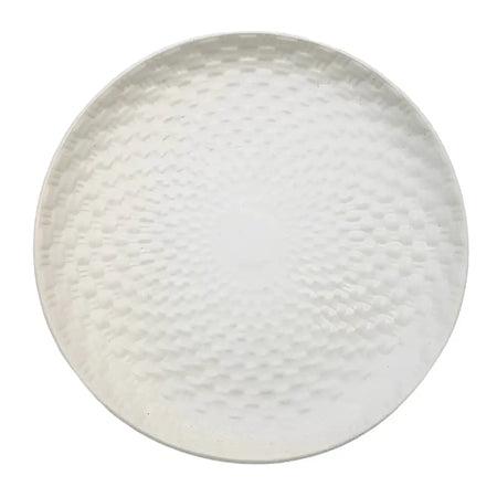 White ceramic plate with a white hammered metal serving tray featuring a textured circular weave design pattern