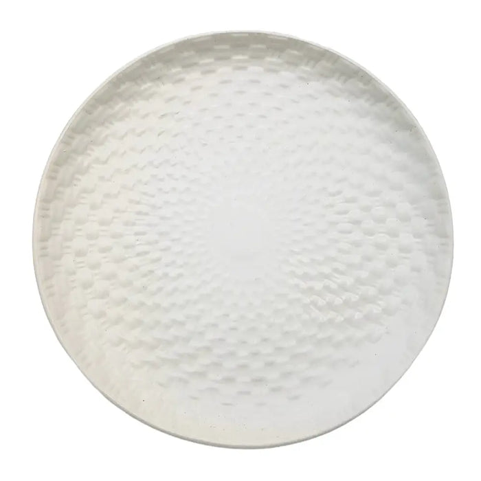 White ceramic plate with a white hammered metal serving tray featuring a textured circular weave design pattern