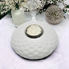 White ceramic tealight holder with textured weave design and metallic cup holding a white lotus shaped tealight