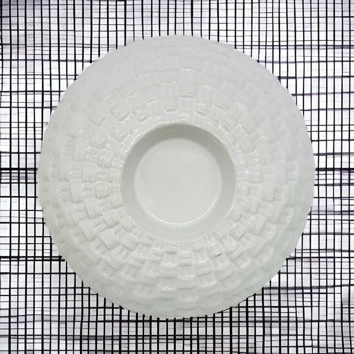 White ceramic tealight holder with a textured woven pattern around the rim made of white ceramic material