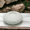 White ceramic tealight holder with a woven textured pattern and a recessed well made of ceramic material