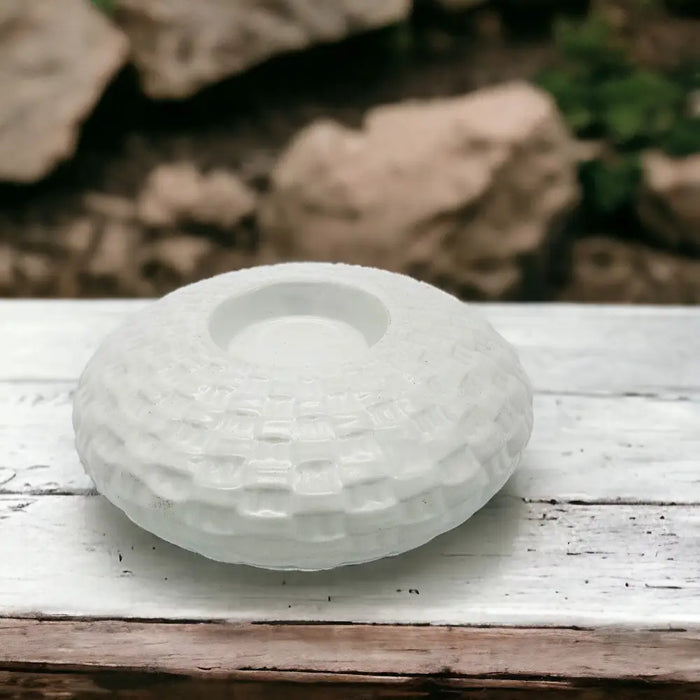 White ceramic tealight holder with a woven textured pattern and a recessed well made of ceramic material