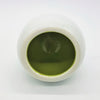 White ceramic tealight holder shown next to a white ceramic tea bowl filled with green matcha powder