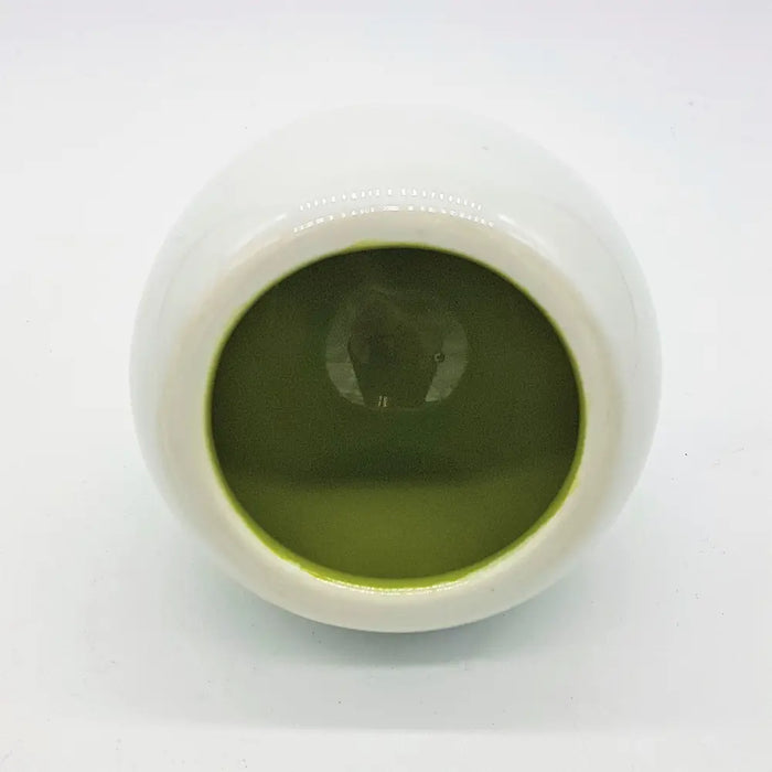 White ceramic tealight holder shown next to a white ceramic tea bowl filled with green matcha powder