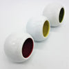 Three white ceramic tealight holders with colorful red yellow and green interiors called traffic lights design