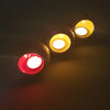 Three spherical tealight holders in red and gold tones with lit candles in a white ceramic traffic lights tealight holder set