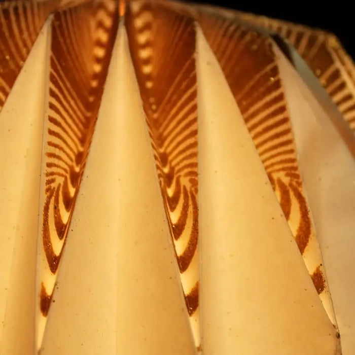 Beige paper lantern with gold glitter zigzag patterns along pleated edges in white origami light shade style