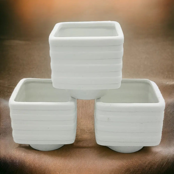 White porcelain tealight holder 6cm x 6cm with a banded square design and horizontal ridged texture