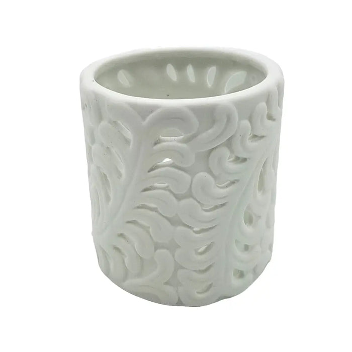 White porcelain tealight holder with intricate swirling leaf pattern cutouts for decorative candle use