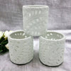 White porcelain tealight holder with intricate fern leaf cutouts made of ceramic for decorative lighting