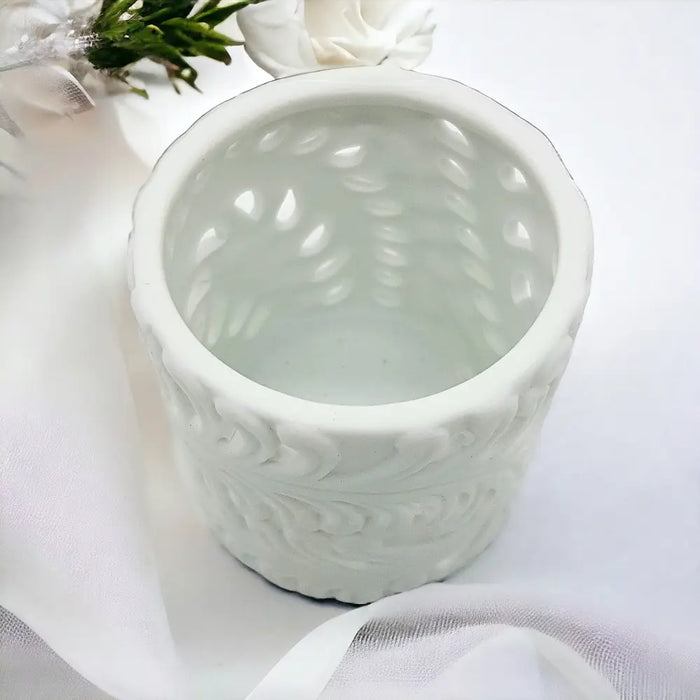 White porcelain tealight holder with cylindrical shape and embossed fern leaf pattern made of ceramic