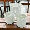 Three white porcelain tealight holders with intricate lace-like moroccan design cutout patterns