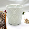 White porcelain tealight holder with intricate lace like cutout patterns in a moroccan design style