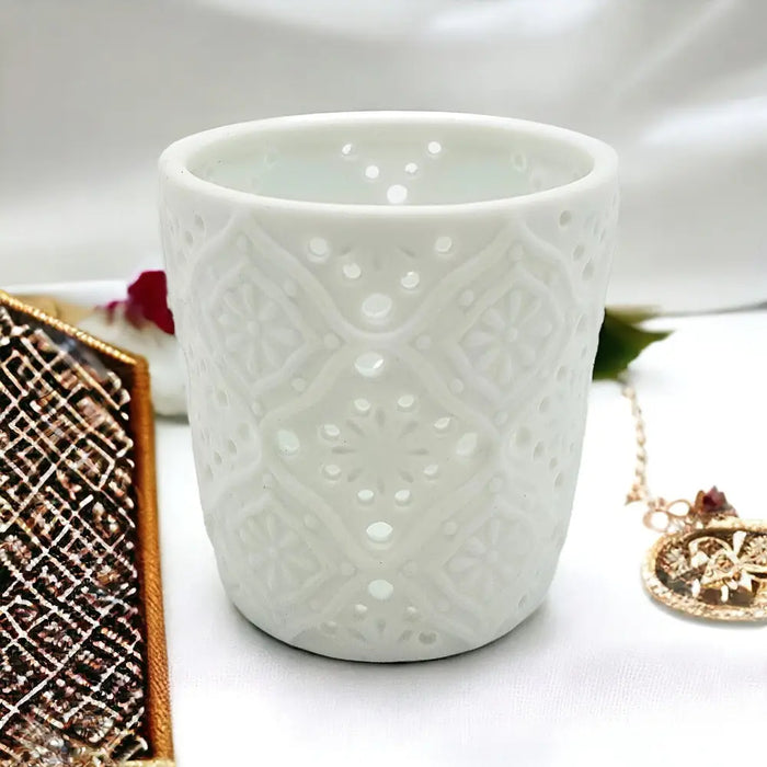 White porcelain tealight holder with intricate lace like cutout patterns in a moroccan design style