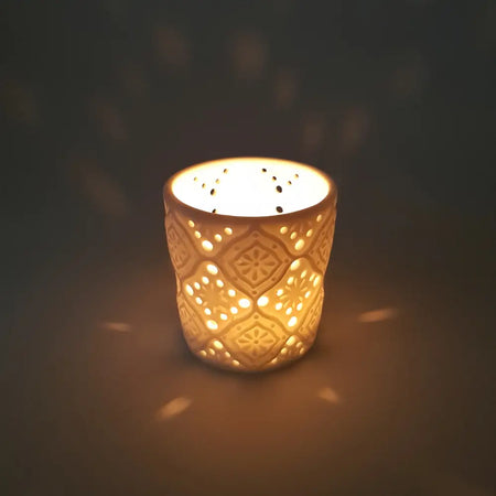 Cream-colored porcelain tealight holder with intricate geometric and floral cut-out patterns in moroccan design