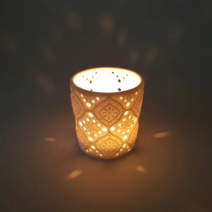 Cream-colored porcelain tealight holder with intricate geometric and floral cut-out patterns in moroccan design