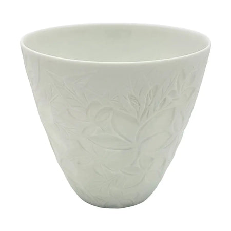 A white porcelain tealight holder with a subtle embossed floral frangipane design in a simple ceramic cup shape